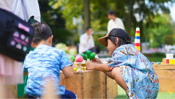 屋外で、木製のおもちゃで遊ぶ2人の子供たち。