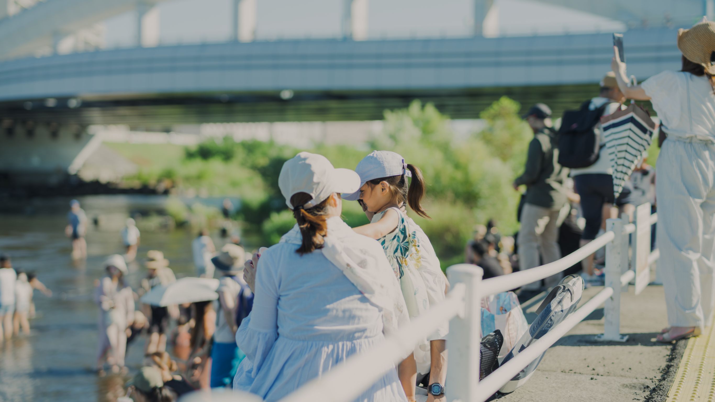 川沿いの公園で水遊びやピクニックを楽しむ多くの人々